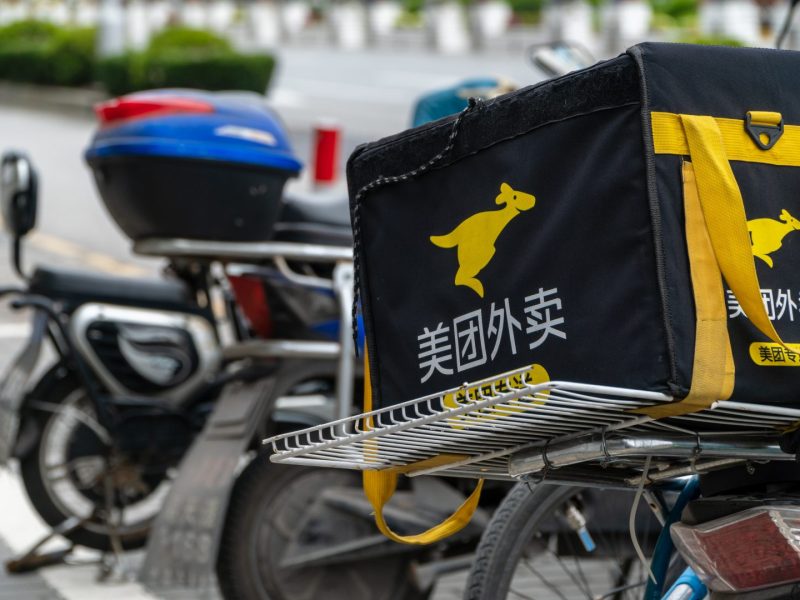 A Meituan-Dianping delivery bag sits atop an e-scooter on the streets of Shanghai on March 22, 2019. delivery drivers